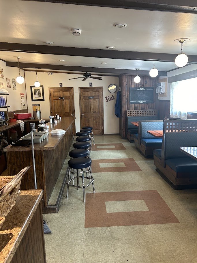 Diner counter view with stools and a service window.